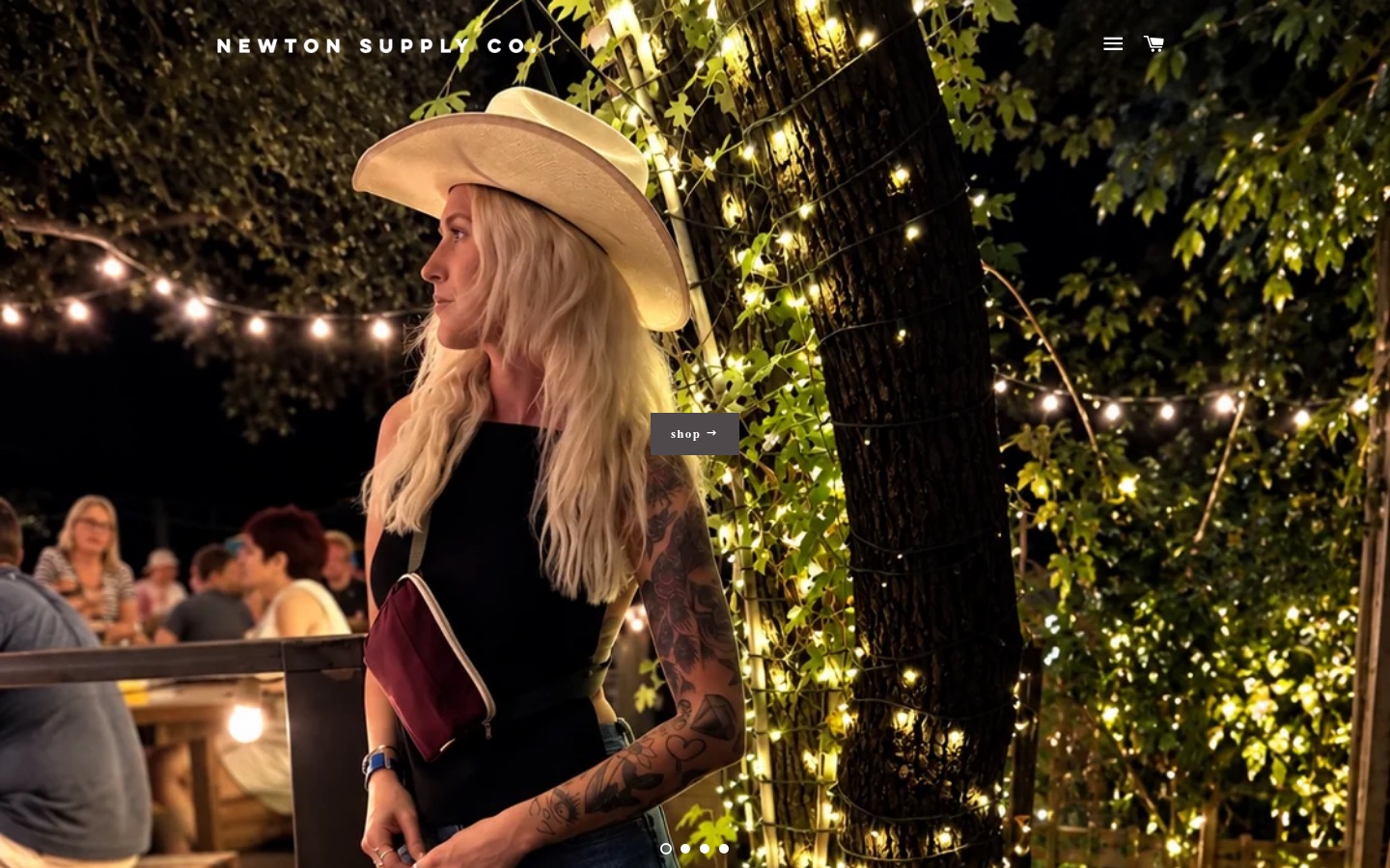 Newton Supply Co homepage: a woman carrying a waxed canvas clutch at night